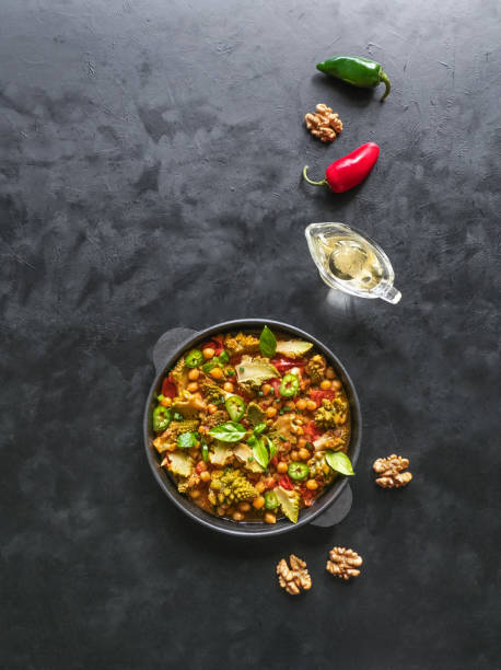 Nutty roasted romanesco curry in a black background. Top view.