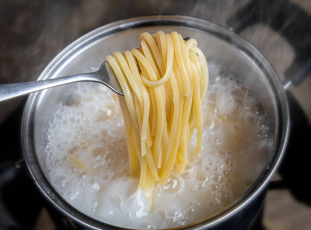 żółty makaron lub spaghetti gotowania we wrzącej wodzie garnka. - wrzący zdjęcia i obrazy z banku zdjęć