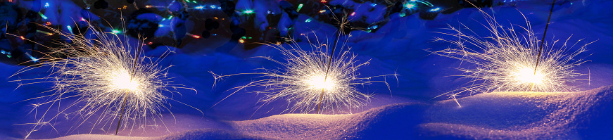 Festive background. Bengal fire, fireworks, spark, snow, bokeh effect. Christmas or New Year. Selective focus, close-up. Banner