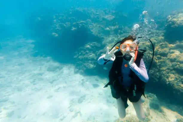 Young girl giving a ok sign while scuba diving in Maragogi, Alagoas, Northeastern Brazil