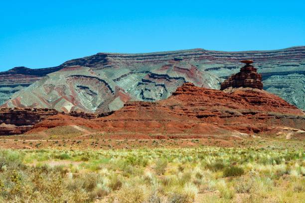 istock View over plain with green dry grass tufts on red and grey sandstone hill formation (butte) against blue sky  - Monument Valley, Utah, Arizona 1175069240