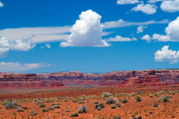 istock View over endless red sand dry waste plain with green grass tufts on sandstone hill formation (buttes) against blue sky with towering white cumulus clouds - Monument Valley, Utah, Arizona 1175069250