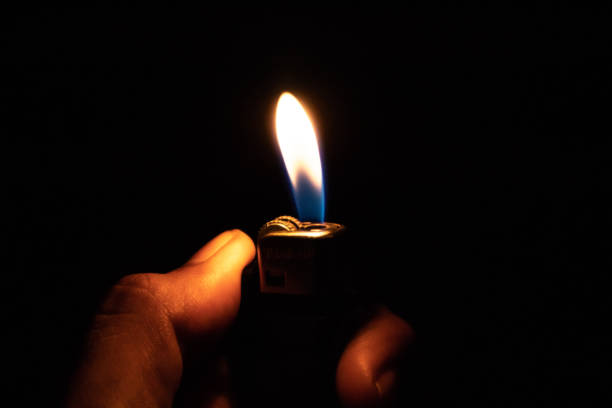 istock Hand holding burning gas lighters on dark background 1175071807