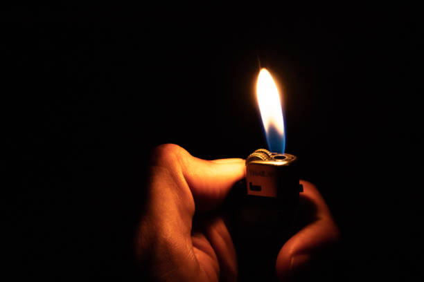 istock Hand holding burning gas lighters on dark background 1175071810