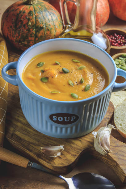 istock Pumpkin soup and organic pumpkins on rustic table. 1175077082
