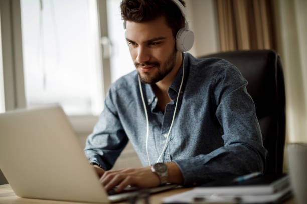 istock Young man using laptop and listening to music 1175077144