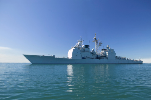 Ticonderoga class aegis guided missile cruiser at sea with a fog bank in the distance.