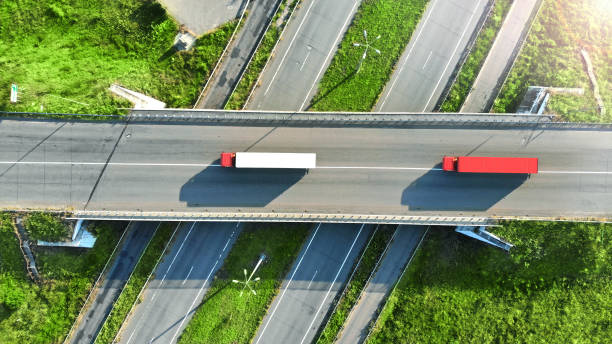 Truck logistics aerial. Two trucks motion by the highway intersection road between fields. View from drone. Truck logistics aerial. Two trucks motion by the highway intersection road between fields. View from drone. truck mode of transport road transportation stock pictures, royalty-free photos & images
