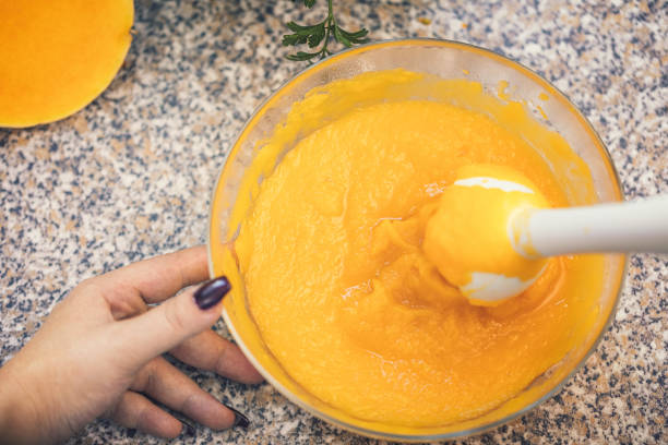 młoda kobieta przygotowuje zupę dyniową w domu - soup pumpkin soup vegetarian food food zdjęcia i obrazy z banku zdjęć