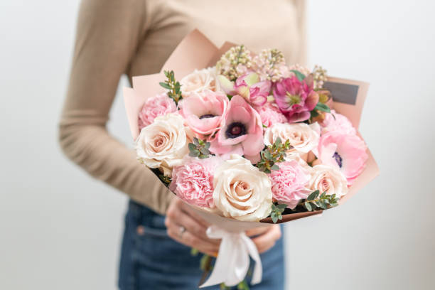 beautiful bouquet of mixed flowers in woman hand. the work of the florist at a flower shop. delicate pastel color. fresh cut flower. pink and white color - flower head bouquet built structure carnation imagens e fotografias de stock