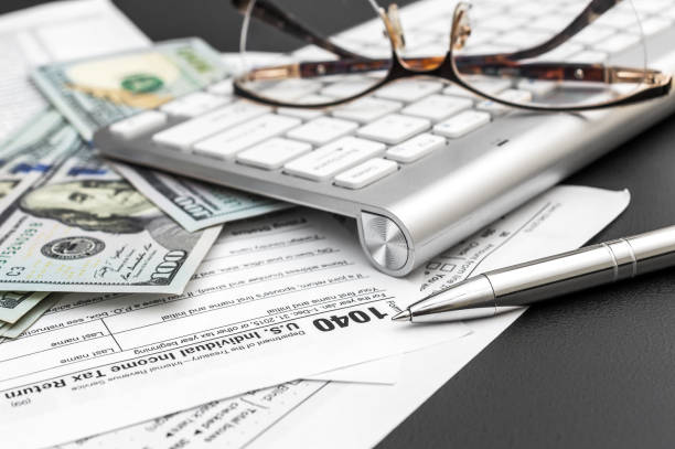 istock Tax form with money and computer keyboard on black background. 1175088759