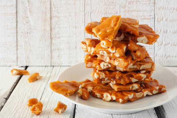 istock Stack of traditional peanut brittle candy pieces against white wood 1175094120