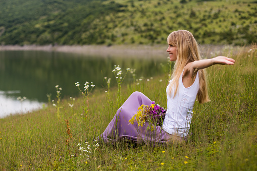 Woman with her arms outstretched enjoys spending her time in beautiful nature.