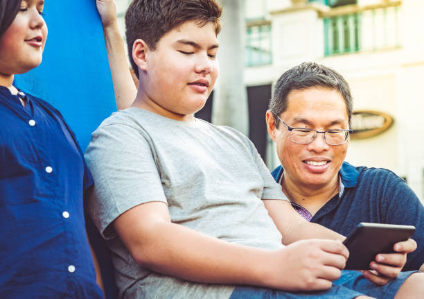 istock Father relaxes outdoors with two preteen children using a digital tablet 1175097443