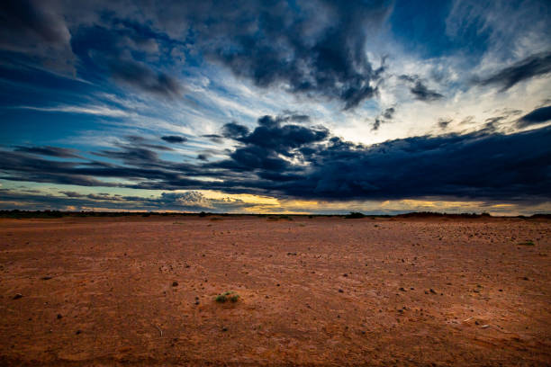 Blue clouds at sunset over hard dry reddish-brown sahelian land with scattered bushes in the distance during summer rainy season outside Niamey capital of Niger Wide angle lens niger stock pictures, royalty-free photos & images