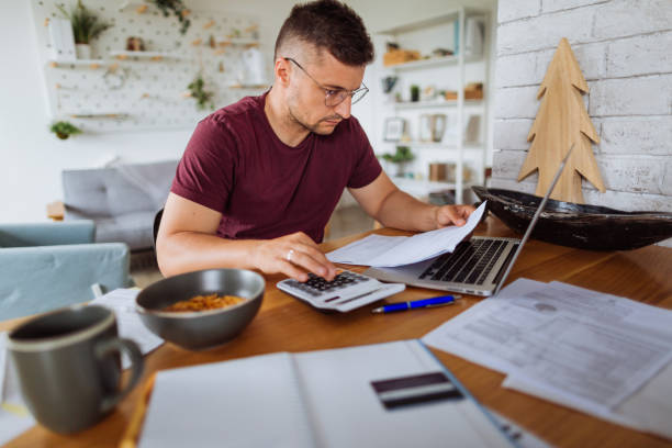 istock Young man at home, paying bills online 1175103107