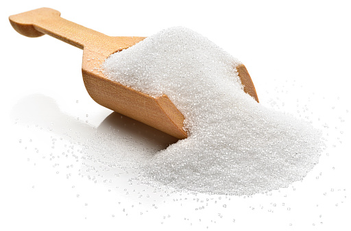 White refined sugar in a serving scoop. 
Isolated on a white background.