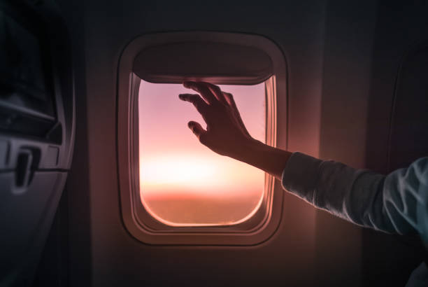 istock Female's hand opening airplane window at sunset. 1175112239