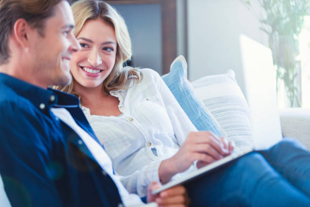 istock Happy couple looking at a laptop computer at home on the sofa. 1175112264