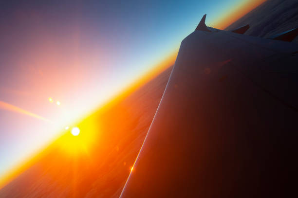 Sunrise over the wing of an airplane blue sky with some clouds. Lens flare.