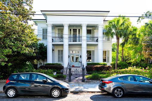 New Orleans, USA - April 23, 2018: Old street historic Garden district in Louisiana city with real estate historic house mansion entrance, cars parked on street road