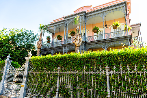 New Orleans, USA - April 23, 2018: Old street historic Garden district in Louisiana city with real estate historic house mansion cast iron fence and gate entrance by garden