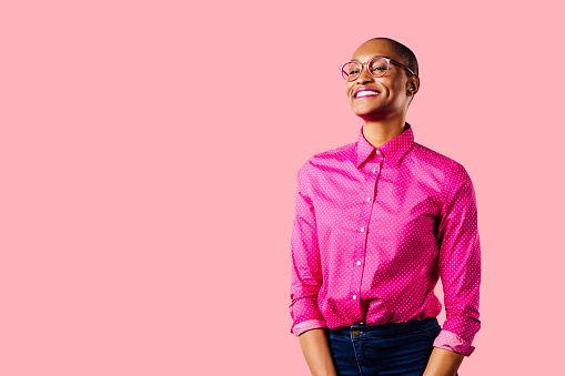 Portrait of a young smiling woman in pink shirt, isolated on pink studio background