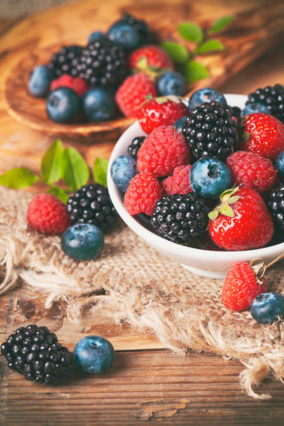 Fresh berries in a bowl on rustic wooden background. stock photo