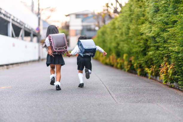 手をつないで走る日本の小学生 - 小学生 ストックフォトと画像