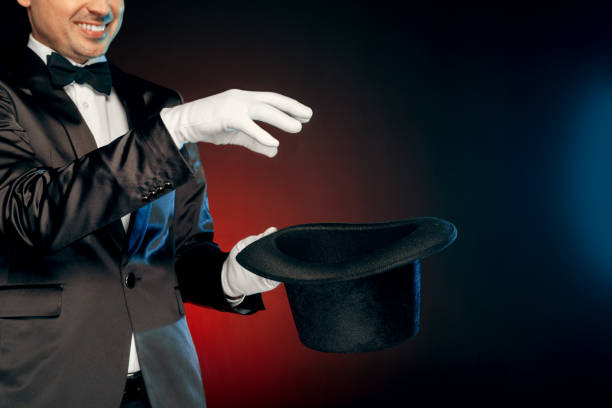 istock Professional Occupation. Showman in suit and gloves standing isolated on wall making tricks with hat close-up smiling cheerful 1175130335