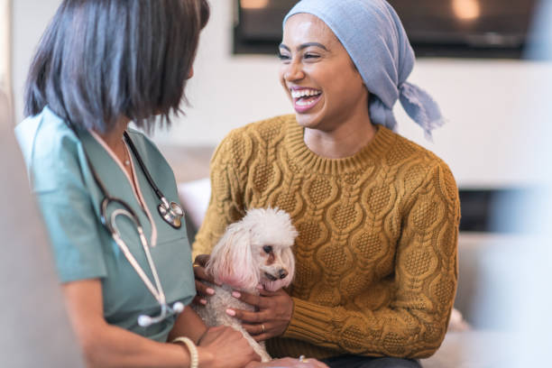 feliz joven con cáncer sostiene perro mascota mientras se reúne con su médico - dog pets advice women fotografías e imágenes de stock