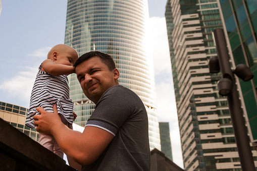 Father and one year old daughter against the sky and skyscrapers. Travel with children, the development of emotional intelligence. Early development