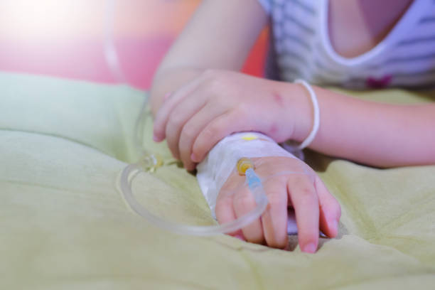 solução intravenosa em pacientes de uma criança mão, feche acima da mão do paciente das crianças que recebe a solução salina iv em hostpital - hostpital - fotografias e filmes do acervo