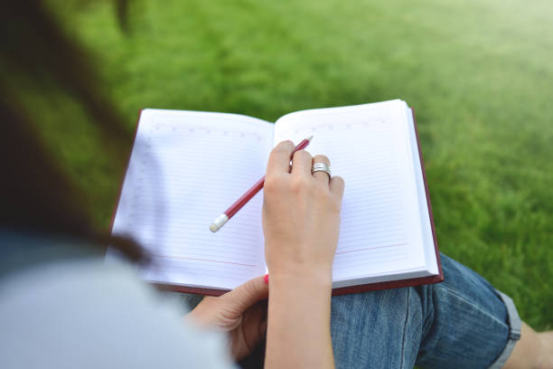 istock close up young women writing on notebook in park, concept in education and knowledge 1175137403