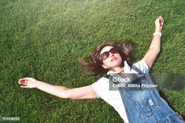 Summervacation Adult Woman Relaxed Lying On Green Grass In An Outdoor Park Girl In Sunglasses Enjoying Nature Lying On Grass Stock Photo - Download Image Now