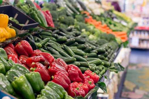 Fresh vegetables piled on stall in the supermarket. Food background. Selective focus on red capsicum