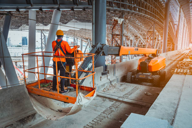 inżynier ubrany w mundur bezpieczeństwa i kask bezpieczeństwa, sterowanie prosto boom lift do dachu budowy na stacji peronu kolejowego sky. - blue construction construction site crane zdjęcia i obrazy z banku zdjęć