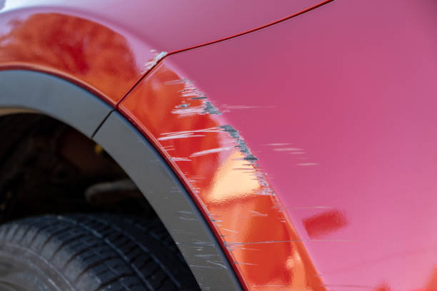 крупным планом глубокие царапины в красной краске бампера автомобиля - dented стоковые фото и изображения
