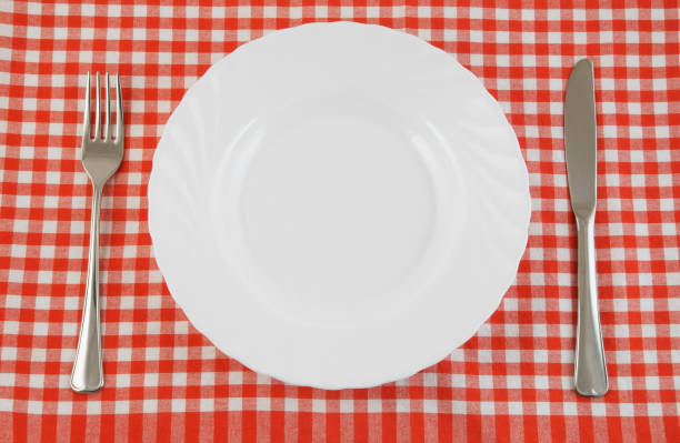 istock Top view of white plate, fork and knife on tablecloth 1175151366