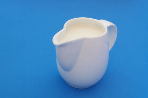 istock Milk in white jug on blue 1175153673