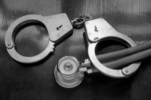 istock Handcuffs and stethoscope on wooden background, malpractice concept 1175157120