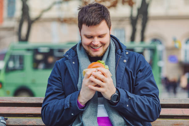 istock young adult man eating hamburger 1175159153