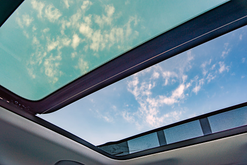 Cielo azul a través de un techo corredizo abierto, vista desde el compartimiento de pasajeros, techo corredizo abierto mirar hacia el cielo. photo