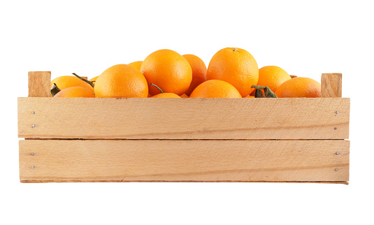 Ripe orange fruits in wooden crate isolated on white background