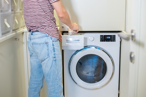 A mid adult man doing the laundry at home.