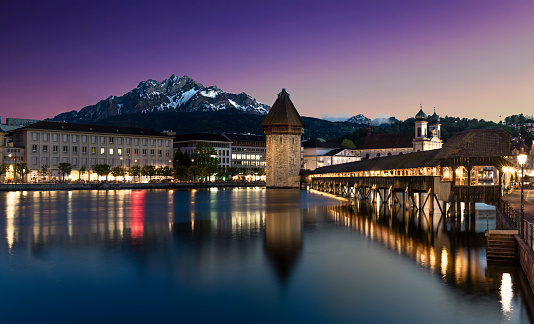 A long exposure shot of the famous Chapel Bridge and Mount Pilatus at night in the city Lucerne, Switzerland.