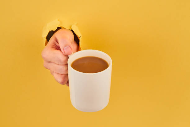 istock Unrecognizable person holding coffee mug on orange background, copy space closeup 1175167588
