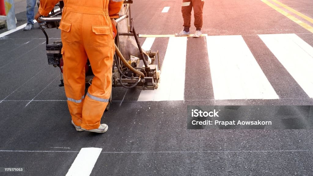 Road worker painting crosswalk on asphalt road Low section of road workers using thermoplastic spray road marking machine to painting pedestrian crosswalk on asphalt road surface in the city Asphalt Stock Photo