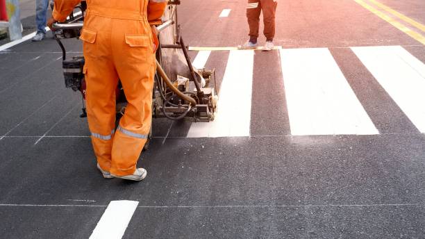 Road worker painting crosswalk on asphalt road Low section of road workers using thermoplastic spray road marking machine to painting pedestrian crosswalk on asphalt road surface in the city road marking stock pictures, royalty-free photos & images
