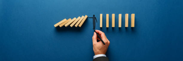 silueta de un hombre haciendo un gesto de parada para evitar que el dominó de madera se derrumbe - change changing form organization leadership fotografías e imágenes de stock